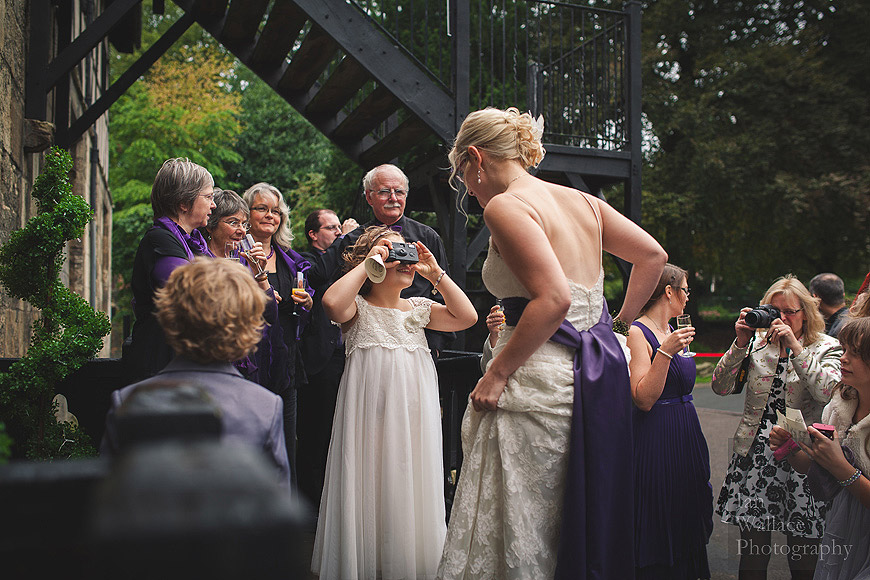 Natural photo of bridesmaid snapping the bride on her wedding day