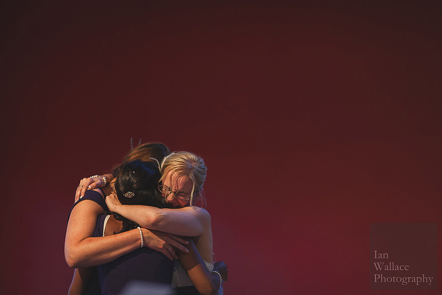 Bride and bridesmaids hugging after an emotional speech.