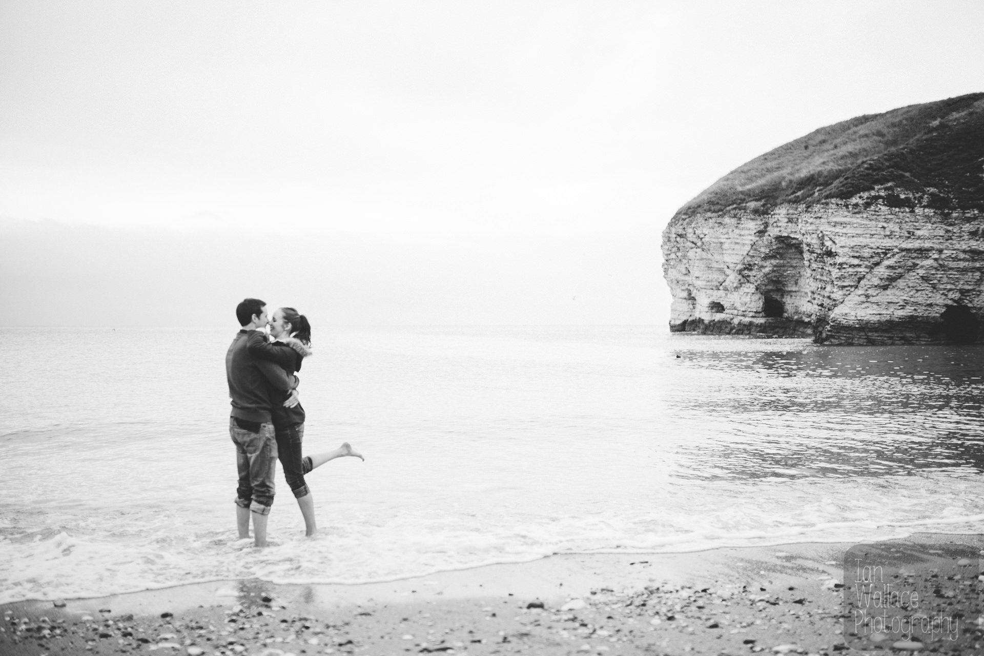 Couple hugging whilst paddling in the sea during a sea-side engagement shoot