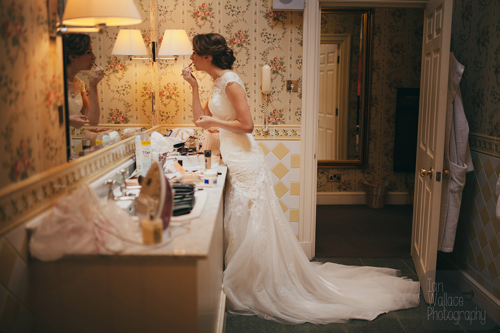 Bride finishing off her make up in the bathroom at Hazlewood Castle