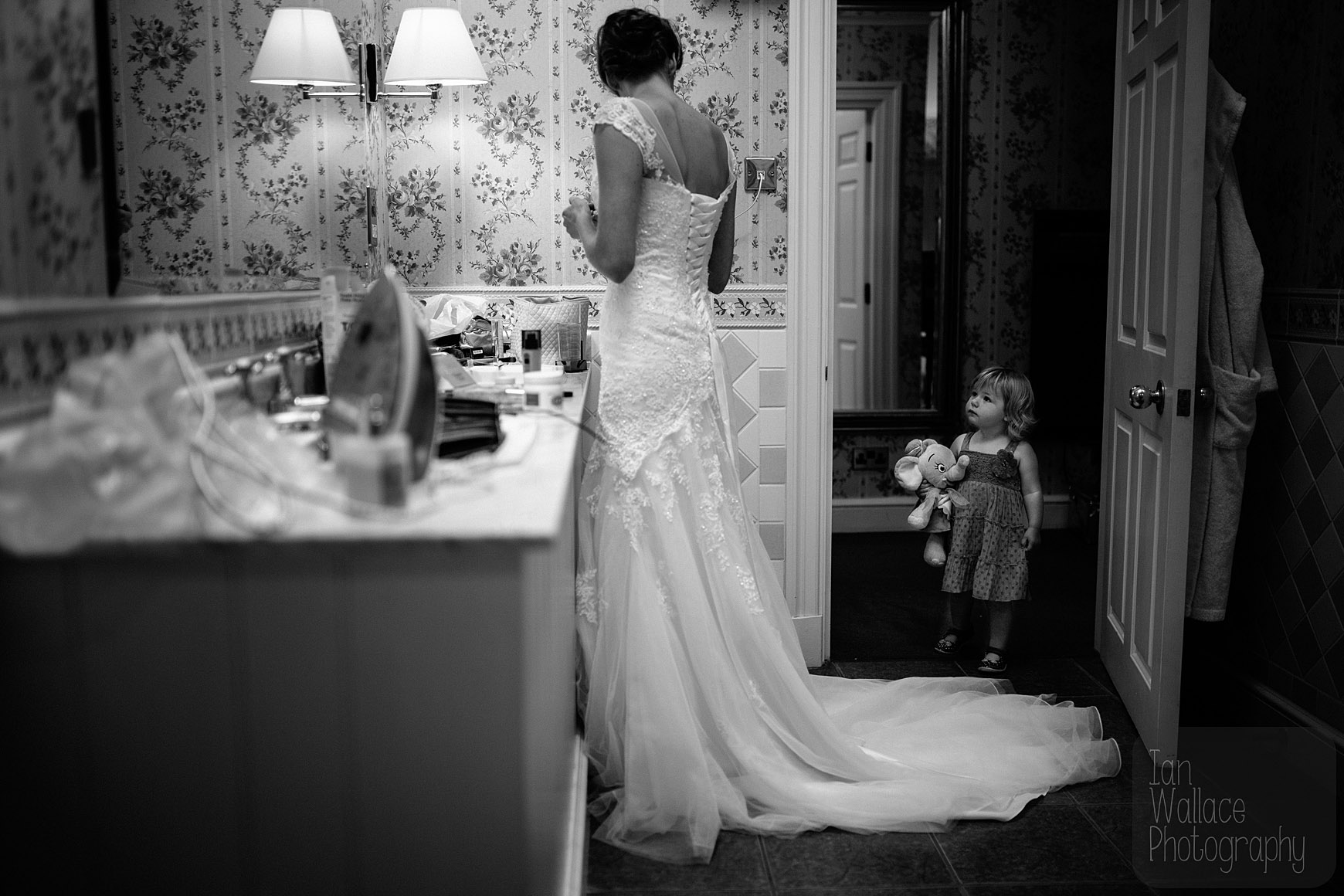 A little girl watches on as the bride finishes getting ready