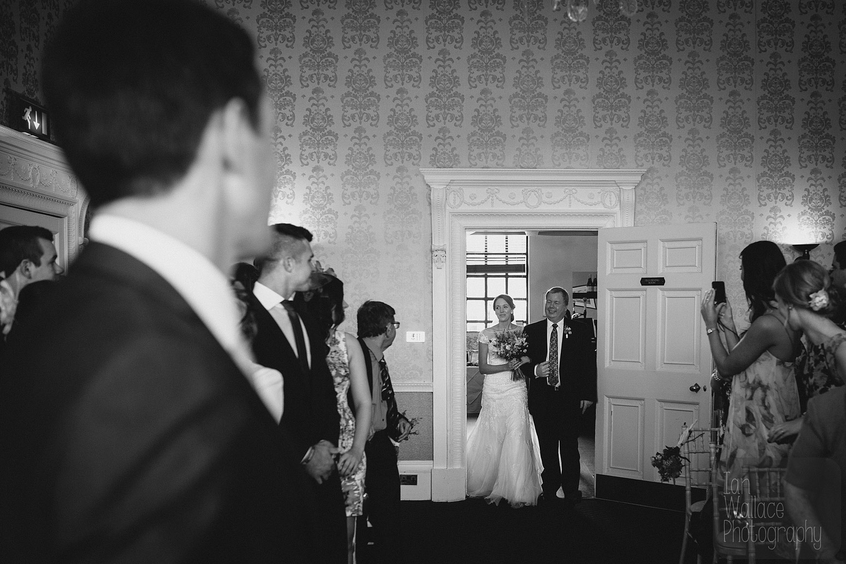 The bride enters the room with her father.