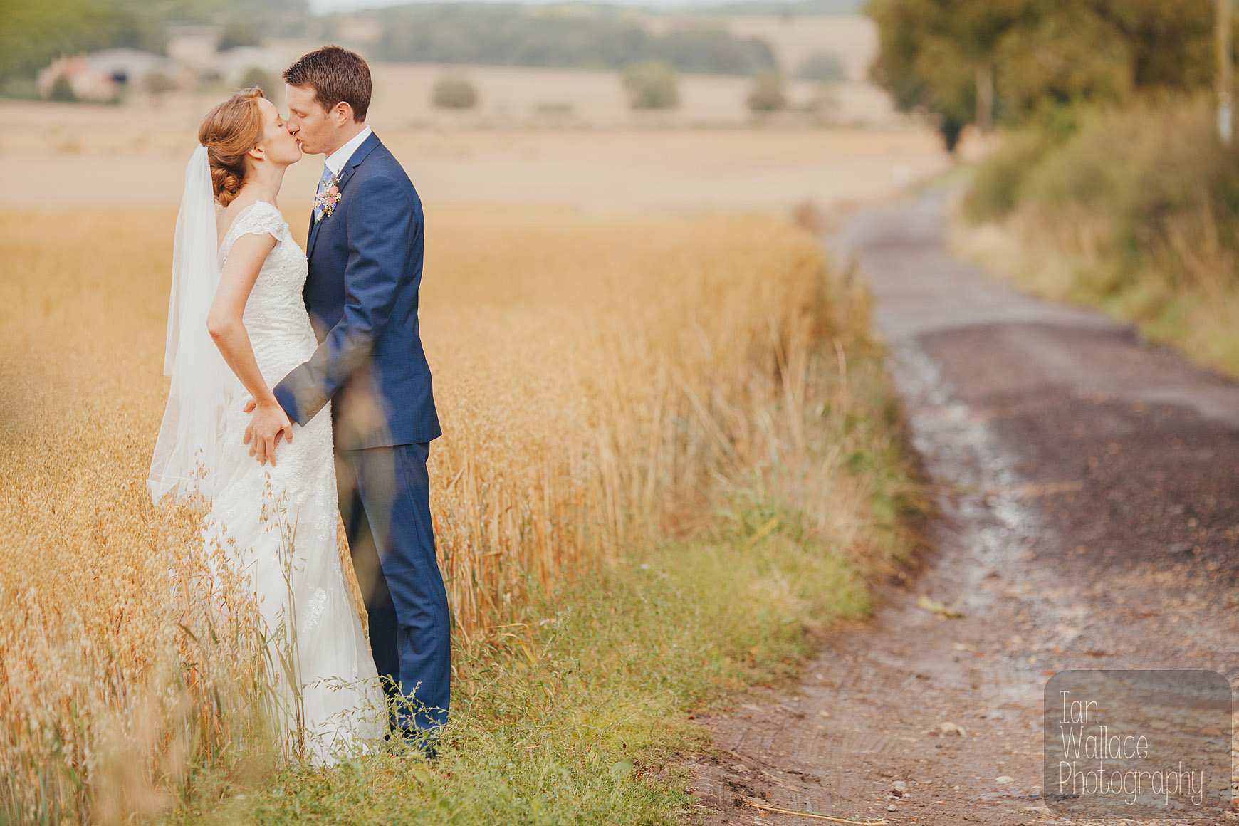 Couple kissing against a corn field and a dirt track