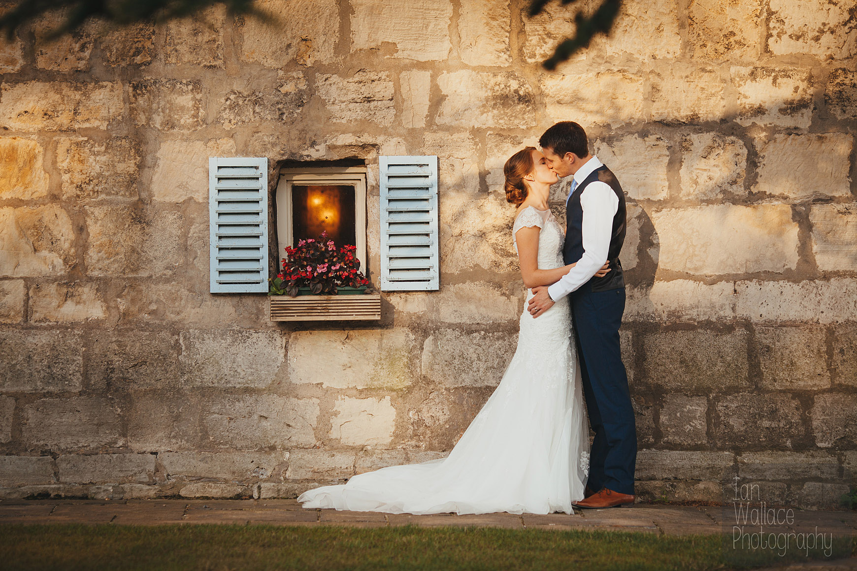 Couple embracing against a castle wall by a cute window