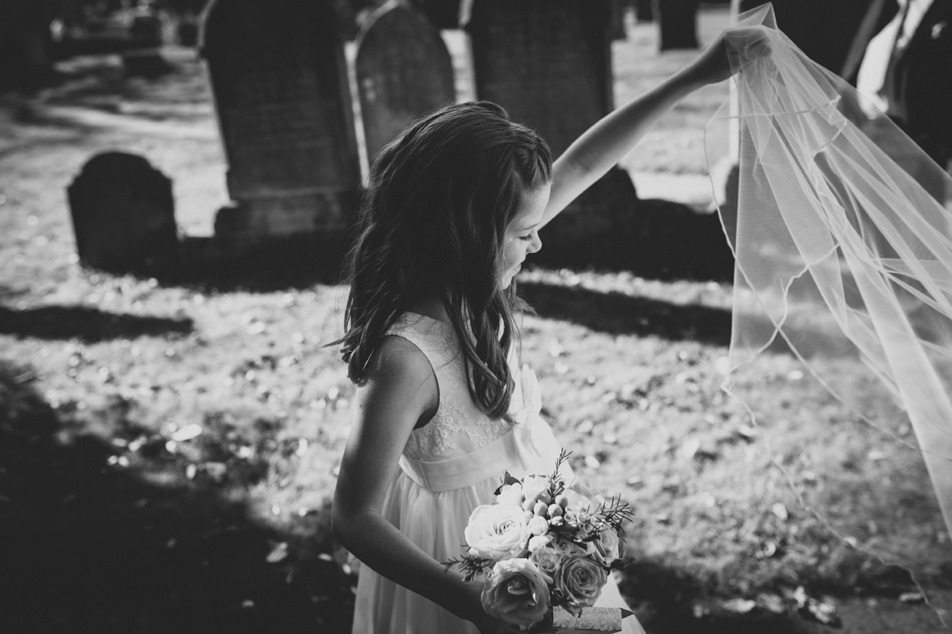 Flowergirl playing with the brides veil alternative wedding photography