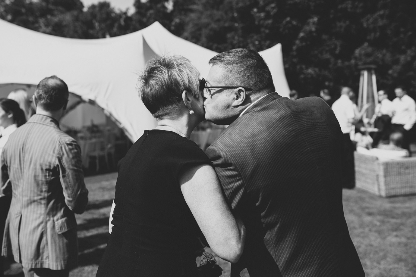 Cheeky kiss, guests at a marquee wedding